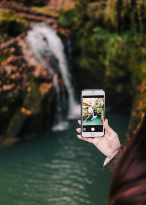 Woman taking photo of a waterfall with her smartphone